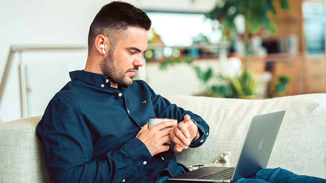 Hombre con portátil mirando su smartwatch