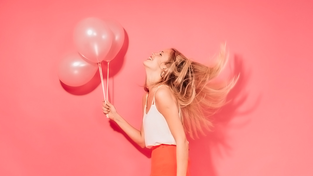 mujer sujetando tres globos rosados