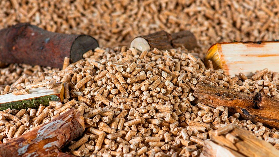 Troncos de madera junto a un montón de pellets