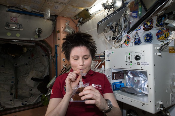 Una mujer bebe un café expreso en el espacio por primera vez al lado de la máquina ISSpresso.