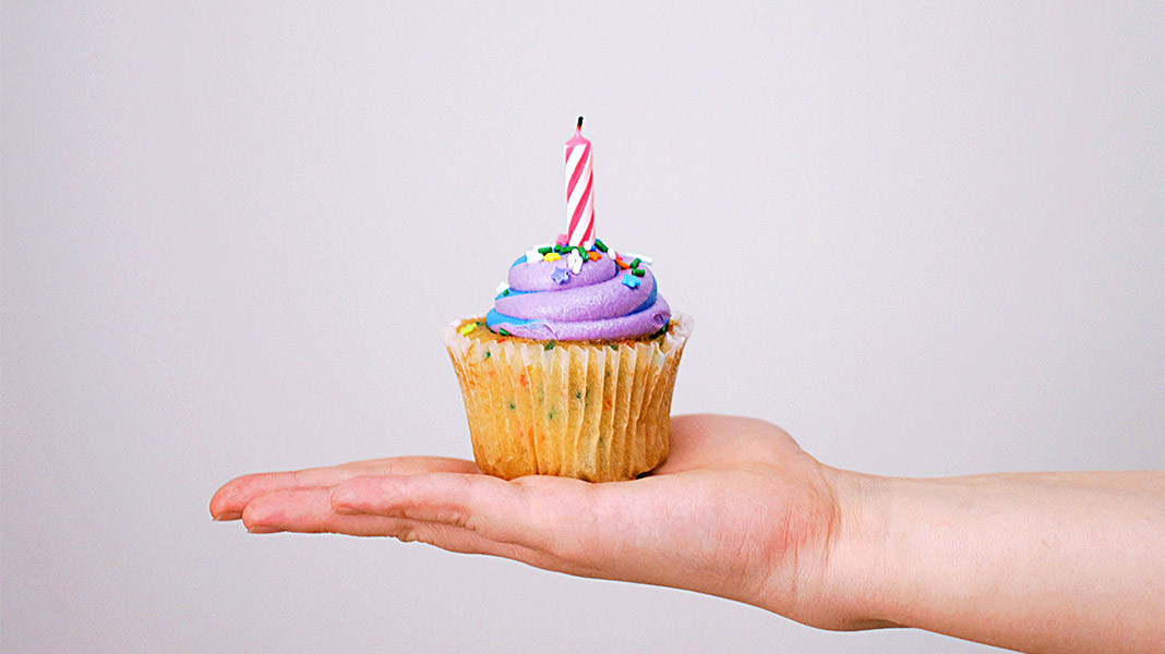 Mano extendida con cupcake con una vela