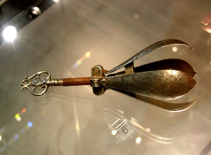 Dispositivo de tortura con forma ovalada compuesta de láminas que se pueden abrir con un tornillo.