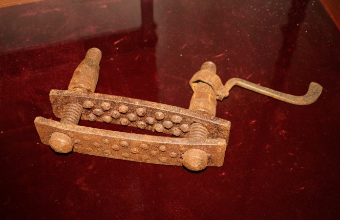 Dispositivo de tortura medieval oxidado muy antiguo, con tornillos y mancuernas para apretar las placas de metal.